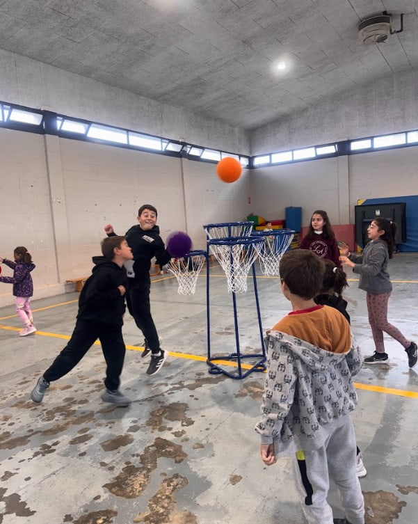 Niños practicando ejercicios con una canasta de minibasket