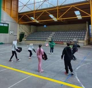 niños practicando el juego balón toca tierra con escudos de espuma